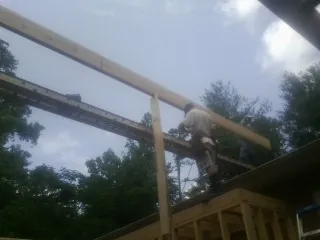 Carpenter setting a ridge beam over a new addition frame — Ice Dam Removal by Roofing Brothers in Marston