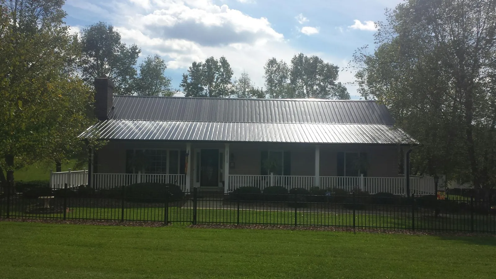 Gray metal roof on a brick ranch with a full width front porch — Gutter Guard Installation work by our crew in Marston