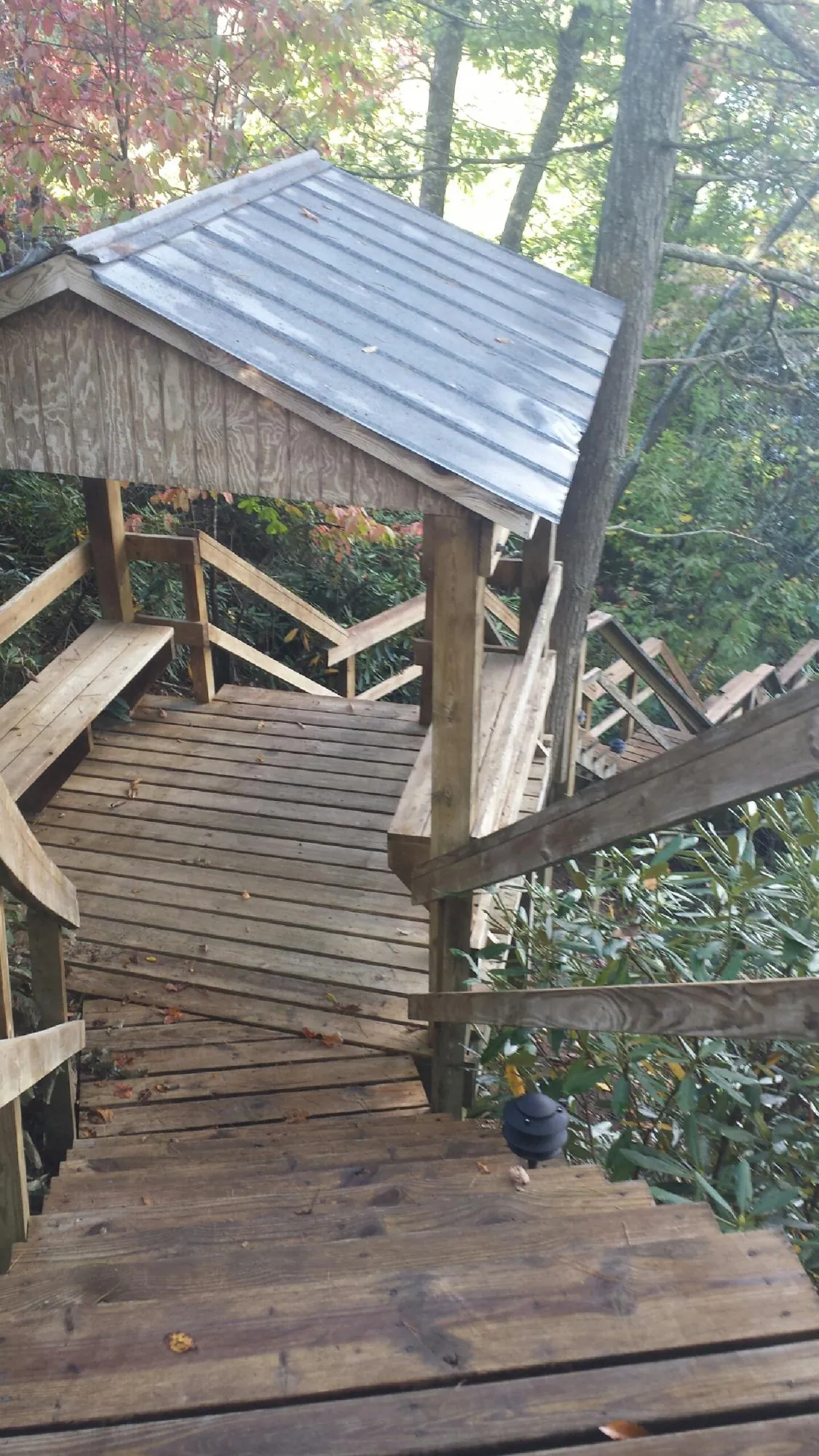 Metal roofed shelter over wooden steps on a wooded walkway — Skylight Repair & Installation work by our crew in Marston