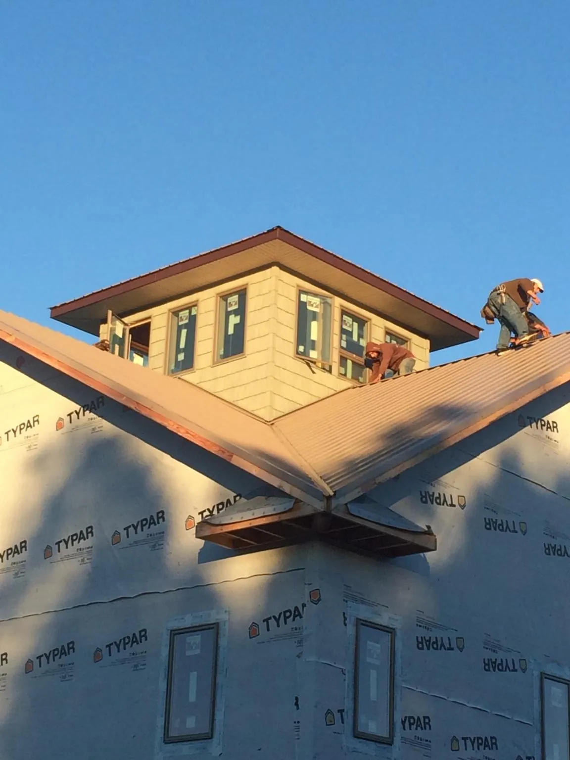 Roofers working around a rooftop cupola on a new metal roof at sunset — Roof Waterproofing in Marston by Roofing Brothers